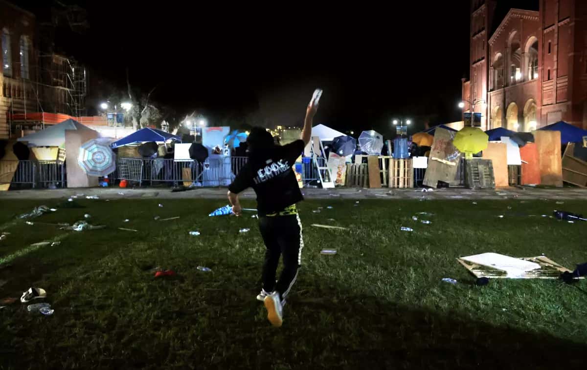 A counterdemonstrator throws a water bottle at a pro-Palestinian encampment at UCLA early Wednesday.